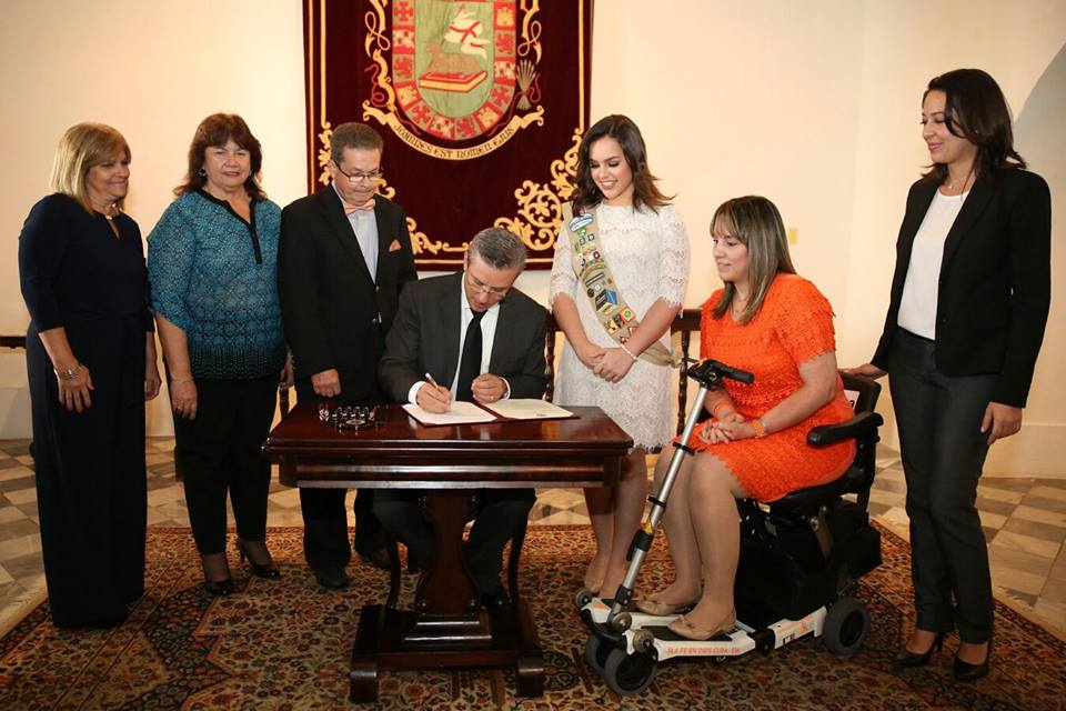 Vilmarie Ocasio looks on as then-Puerto Rico Governor Alejandro Garcia Padilla signs Law 85, which created a mandatory registry of people with MS in Puerto Rico. /Courtesy Vilmarie Ocasio