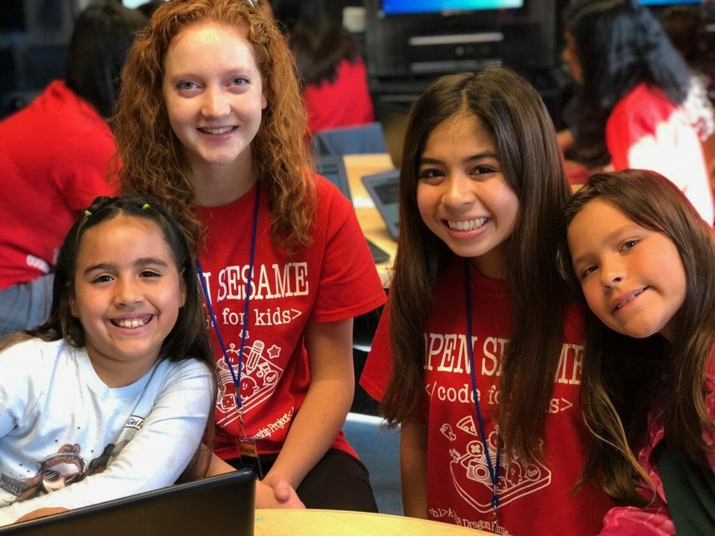 Katherine, left, and Milan pose with some of the over 300 children they have helped to teach coding to through Open Sesame./Courtesy Open Sesame