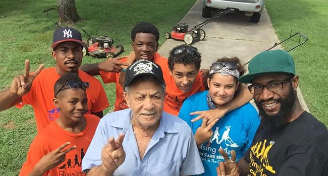 Rodney Smith (left), joined by a group of youth volunteers, provided lawn care services for this man after a stroke left him unable to care for his yard on his own.
