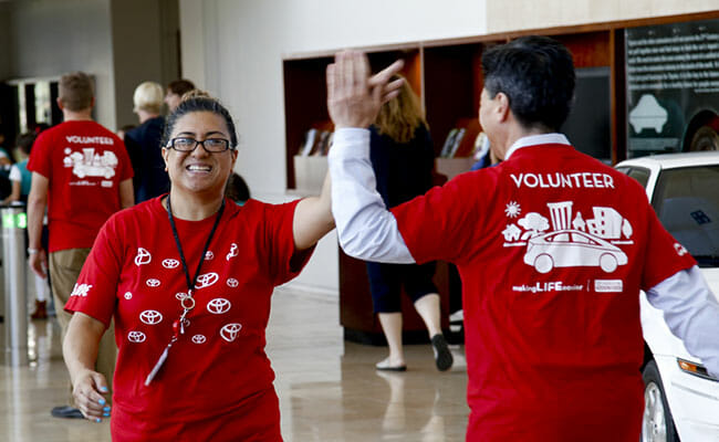 Toyota Financial Services team members high five on their way to teach a financial empowerment activity to Girl Scouts.