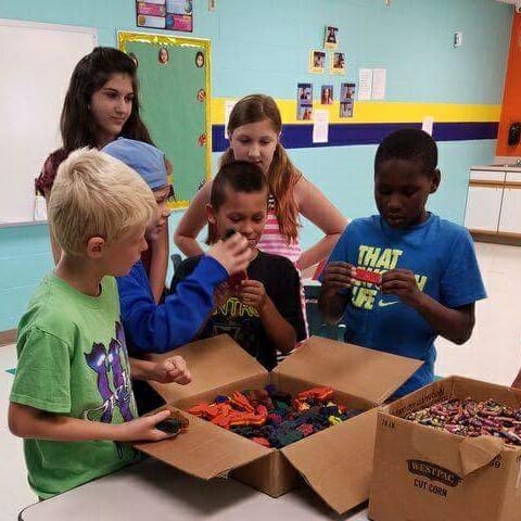 Abby and Riley donate crayons to local children.