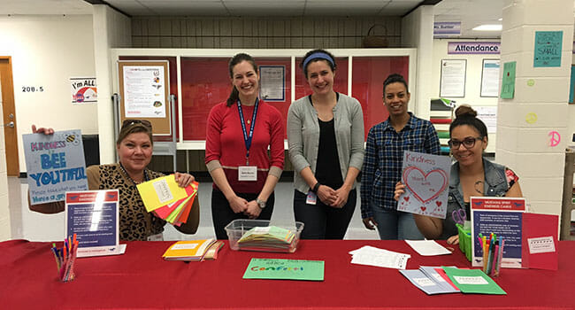Angela Collins and fellow volunteers running the "appreciation station” at Mann Middle School, where students wrote weekly anonymous notes to their classmates to help spread kindness throughout the school. From left: Angela Collins, Katie Bianco, Laura Roberts, Daisy Ortiz-Wynne and Yvette Thomas.