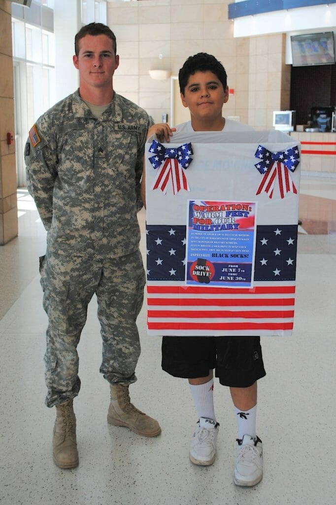 Evan pictured with a service member while spreading the word about his sock drive for the military./Courtesy Merry Grace