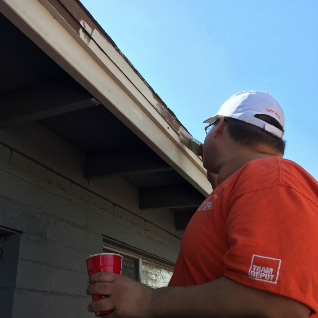 A Home Depot volunteer paints the trim of a house to bring it back into city code compliance.