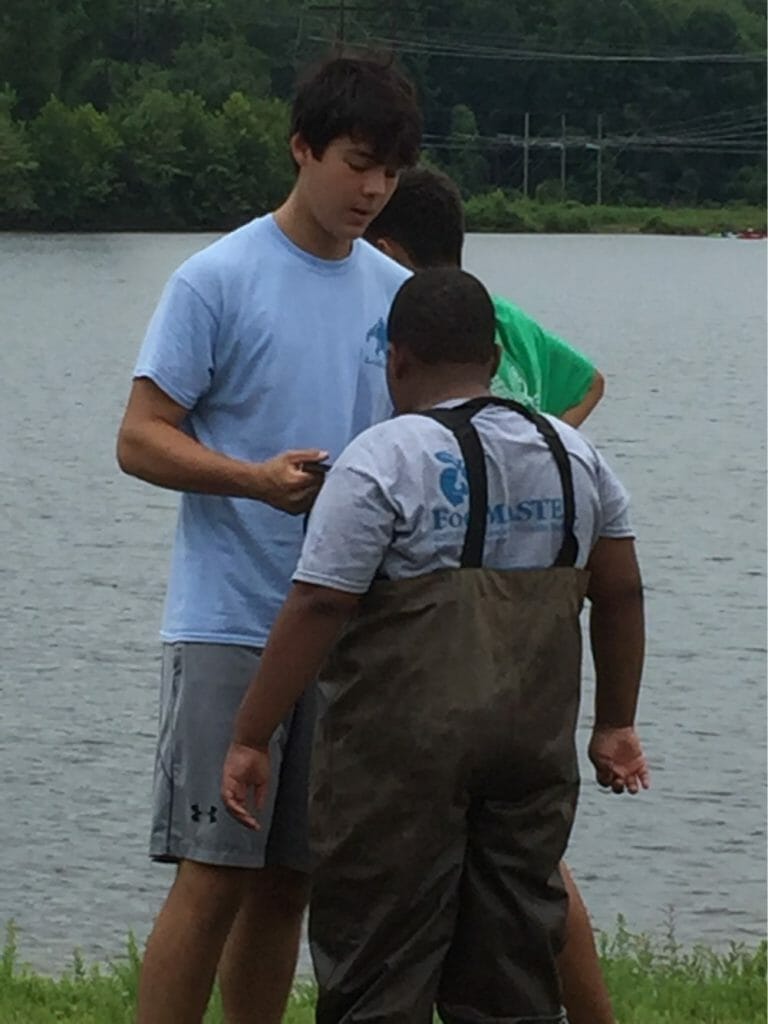 Liam helps a camper put on waders in preparation for an outdoor class on water science and quality./Courtesy Liam Dao