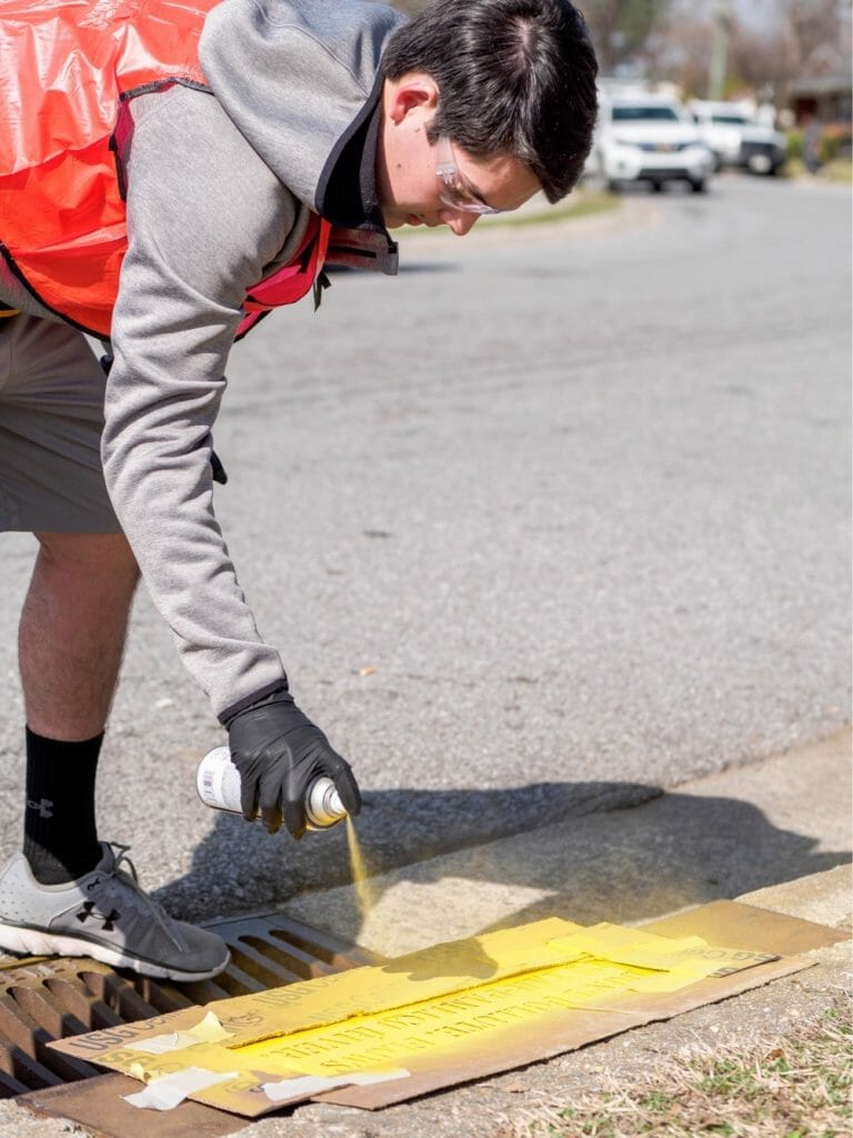 Liam paints a storm drain with an anti-pollution message to caution people from using it for waste disposal./Courtesy Liam Dao