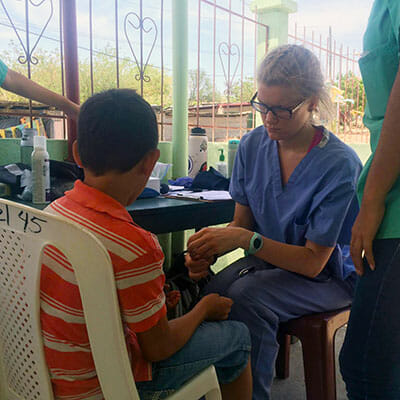 Sydney Lawrence checks a child's vital signs at an HOLA medical clinic.