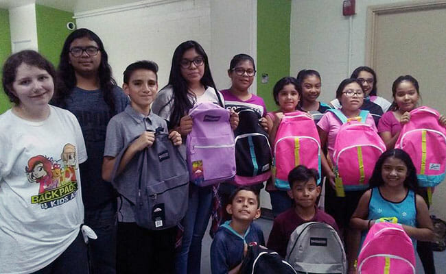 Kaitlyn, left, with students receiving backpacks from Backpacks 4 Kids AZ.