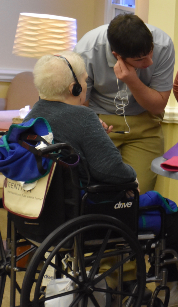 Colby Ellis helps set up an iPod for a nursing home resident./Courtesy Juli Ennis