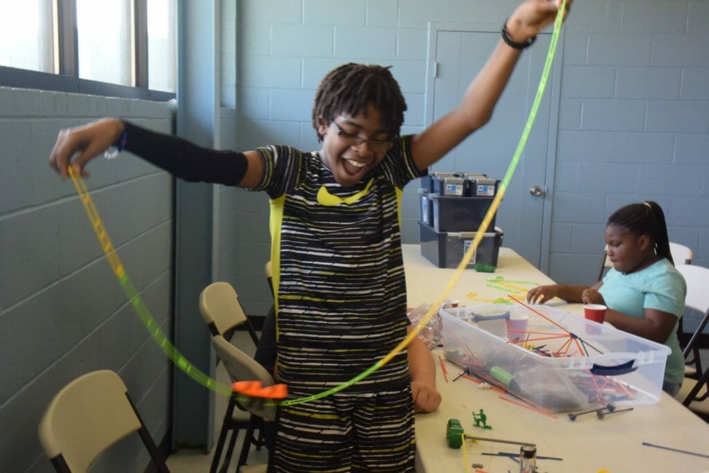 An Operation Empower member experiments with plastic car tracks during a "Makerspace" STEM workshop./Courtesy Curt Fendley