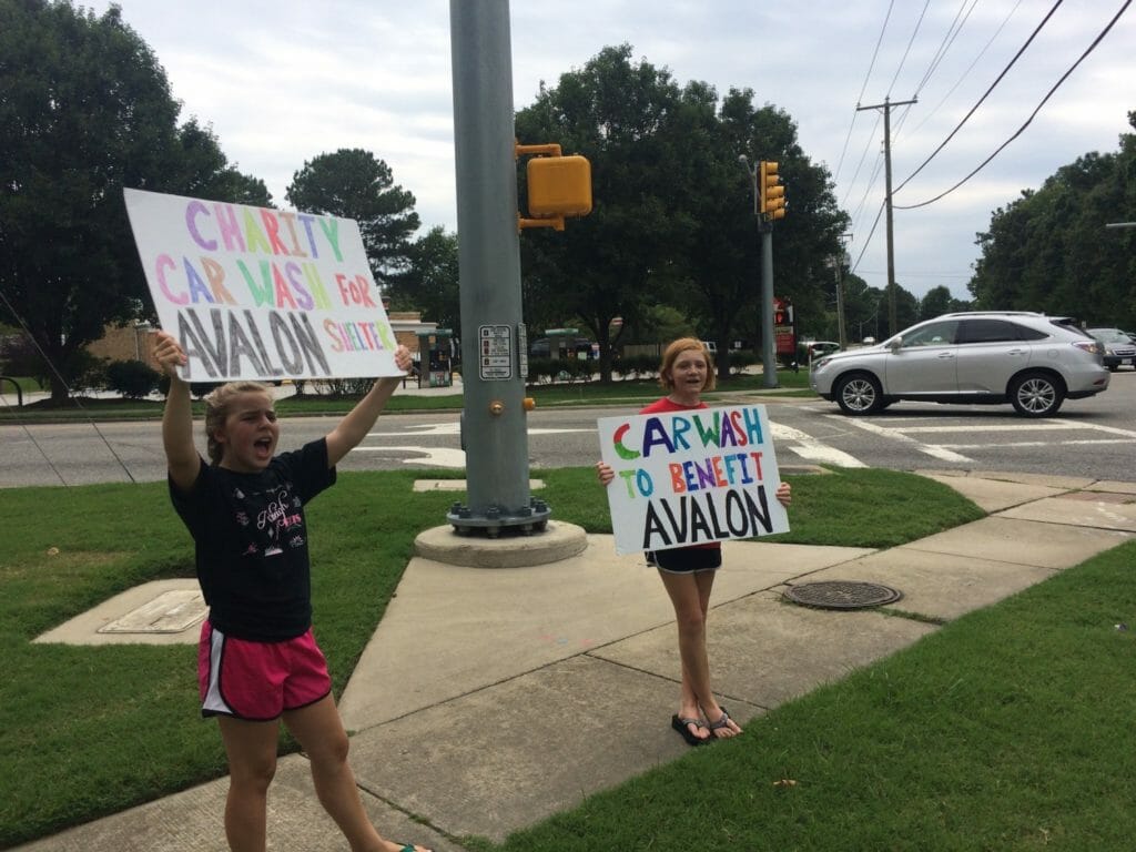 Emma Grace Stelljes and a fellow volunteer hold up signs advertising their carwash benefiting a local shelter./Courtesy Drew Stelljes