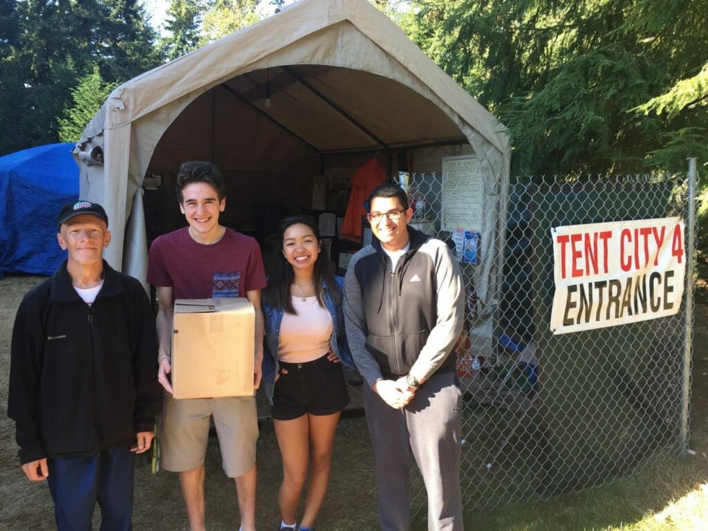 Mai Nguyen (second from right) and fellow volunteers donating books and donuts to Tent City 4 in partnership with the Literacy Crusade./Courtesy Mai Nguyen