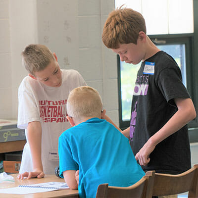 Chandler Wimmer helps students assemble a robot.