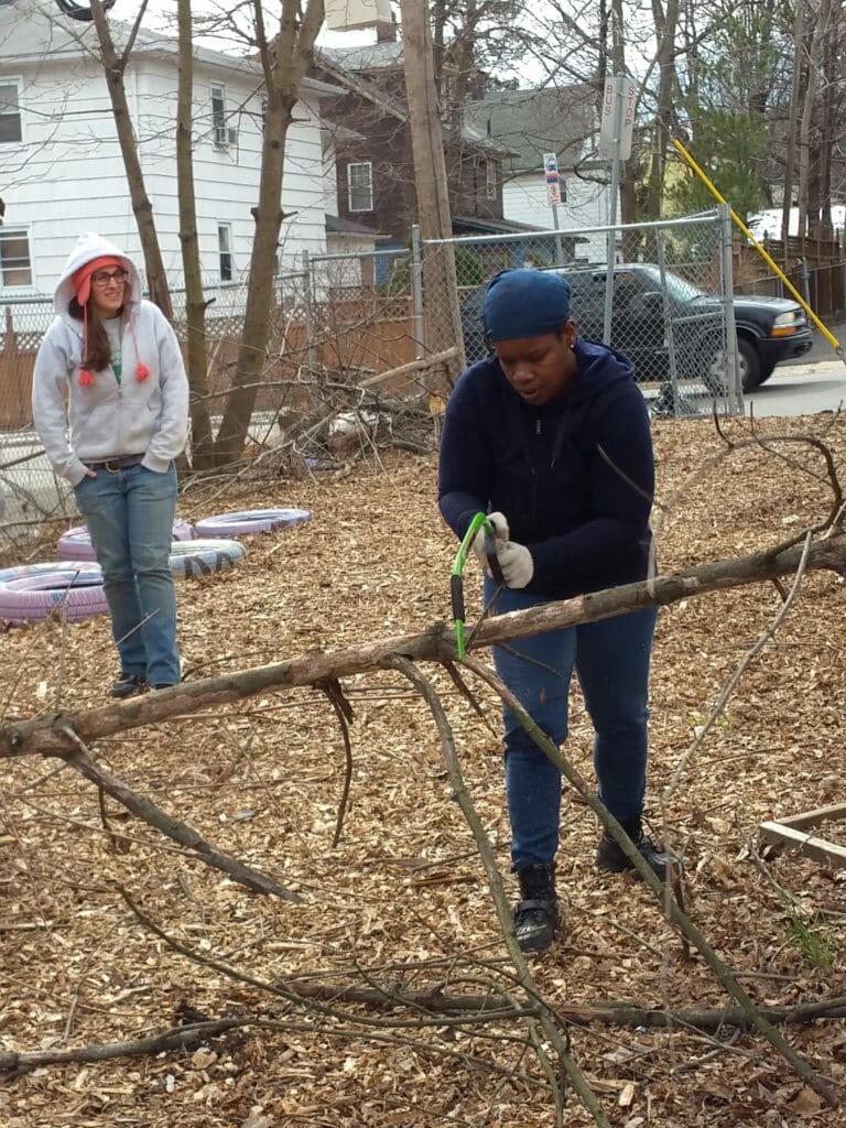 Amina saws a tree limb during a beautification event for the 18th Avenue Heart of Vailsburg Health Havens Garden./Courtesy Amina Hylton 