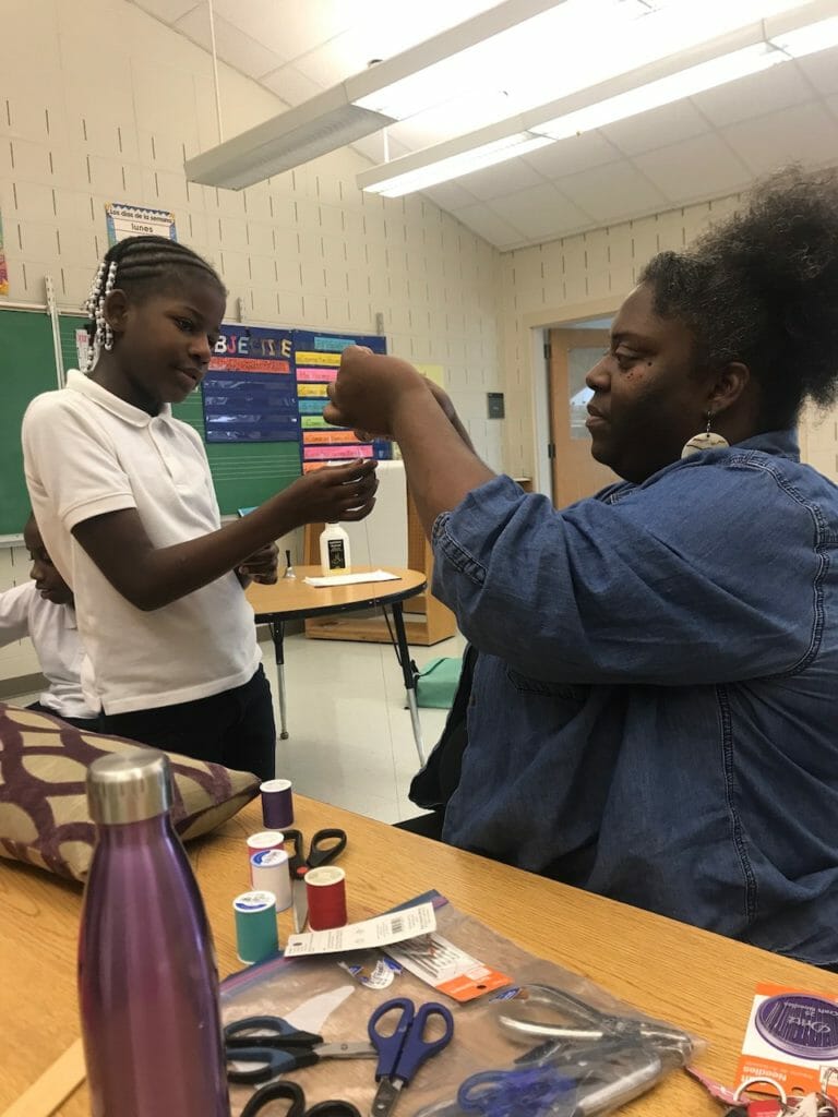 KaCey teaching a sewing technique to a student at Cleveland Avenue Elementary School./Courtesy KaCey Venning