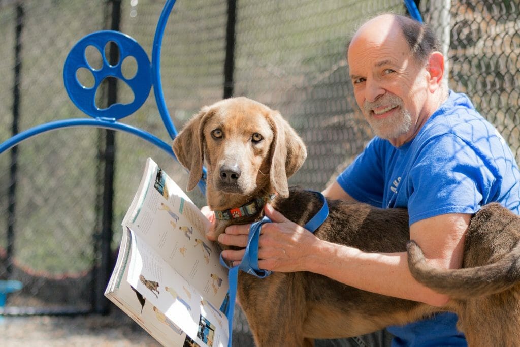 Elliot volunteers full-time at the Asheville Humane Society working with the animal behavior team. Here he is pictured with one of the dogs, Cooper./Courtesy Caren Harris Photography