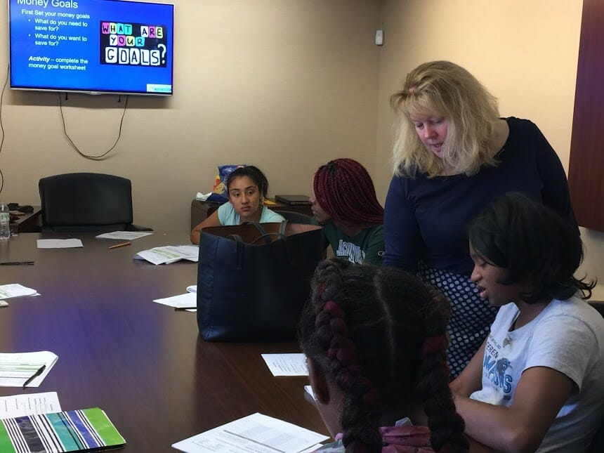 Liz (standing) has spent more than 2,000 hours in the past three years teaching financial literacy to at-risk young girls. Here, Liz teaches a budgeting class in the community./Courtesy Liz Mockler