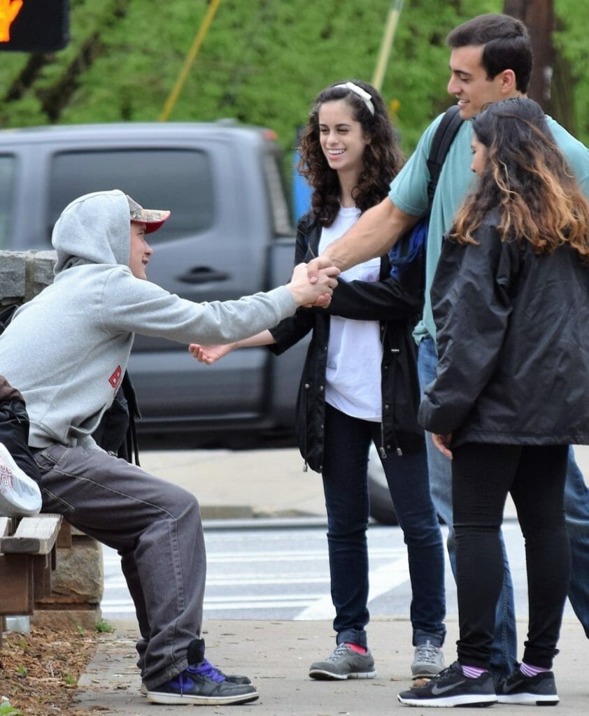 Young man experiencing homelessness shakes hands with Zack Leitz after receiving a backpack from several volunteers./Courtesy Zack Leitz