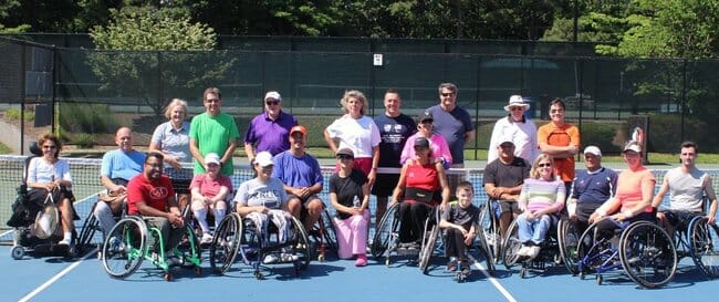 Volunteers and wheelchair tennis clinic participants come together after a successful day on the court. 