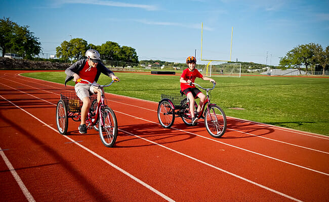 Jake Reid provides encouragement to Special Olympics track athlete Carter during a practice lap.
