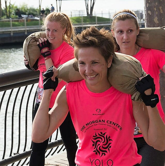 Danielle Taylor (center) carries a heavy sandbag while participating in a YOLO Strong obstacle course run./ Courtesy Danielle Taylor