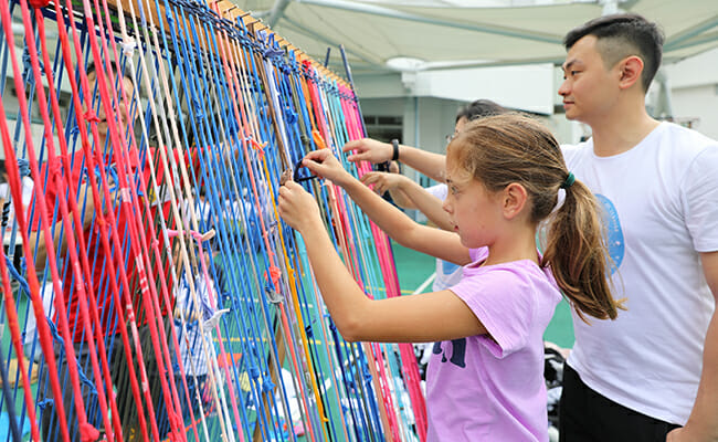 Family members turn unwanted textile materials into a large community rug at HandsOn Hong Kong's Pokfulam Family Volunteer Day event.