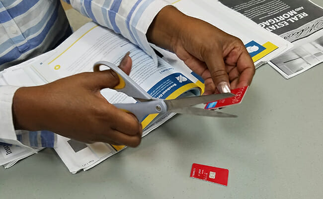 A participant in one of Martina’s financial literacy cuts up one of her credit cards.