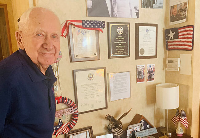 Gene Neeley stands near his wall of fame, a place where he keeps cherished memories and recognition from his time in service. 