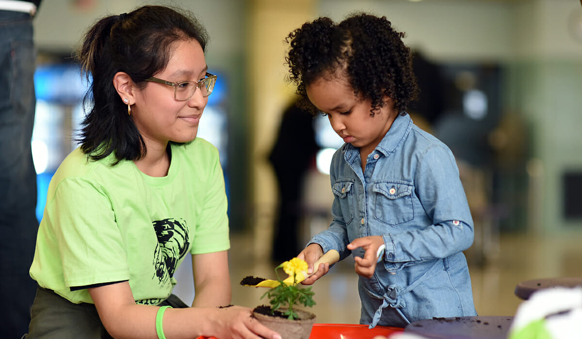 Adult volunteer engages with a young child during a school service project