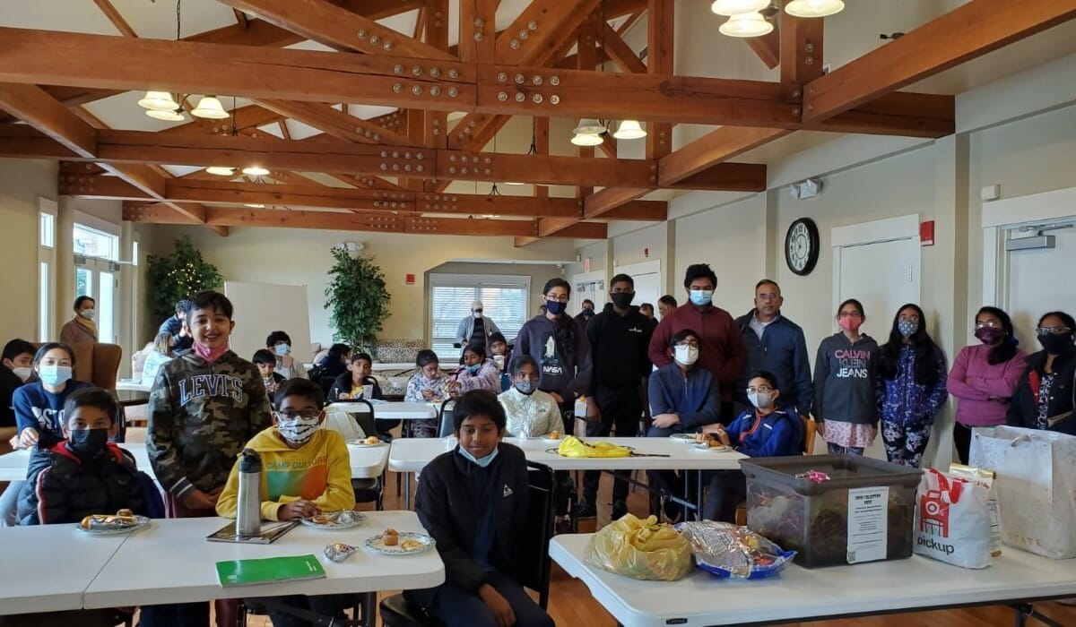 Group of people in a large room seated around folding tables