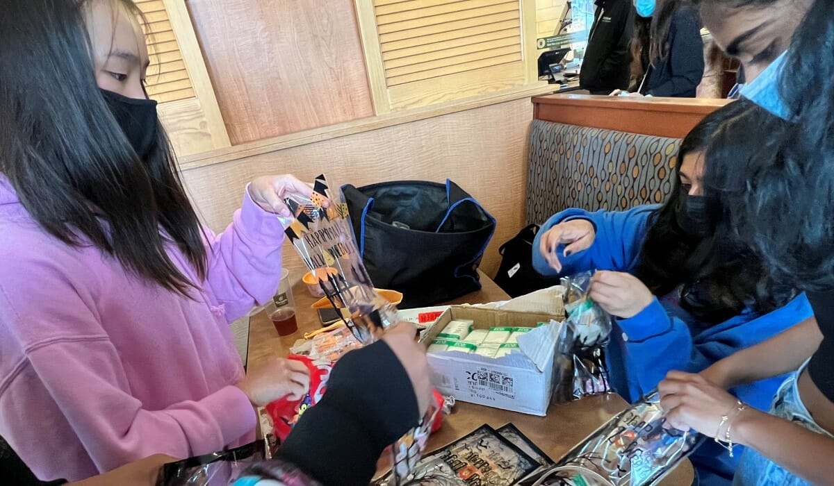 Group of teenage girls packing items into bags decorated for Halloween