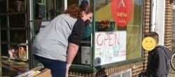 Woman and a small boy standing outside a food pantry with boxes of donations