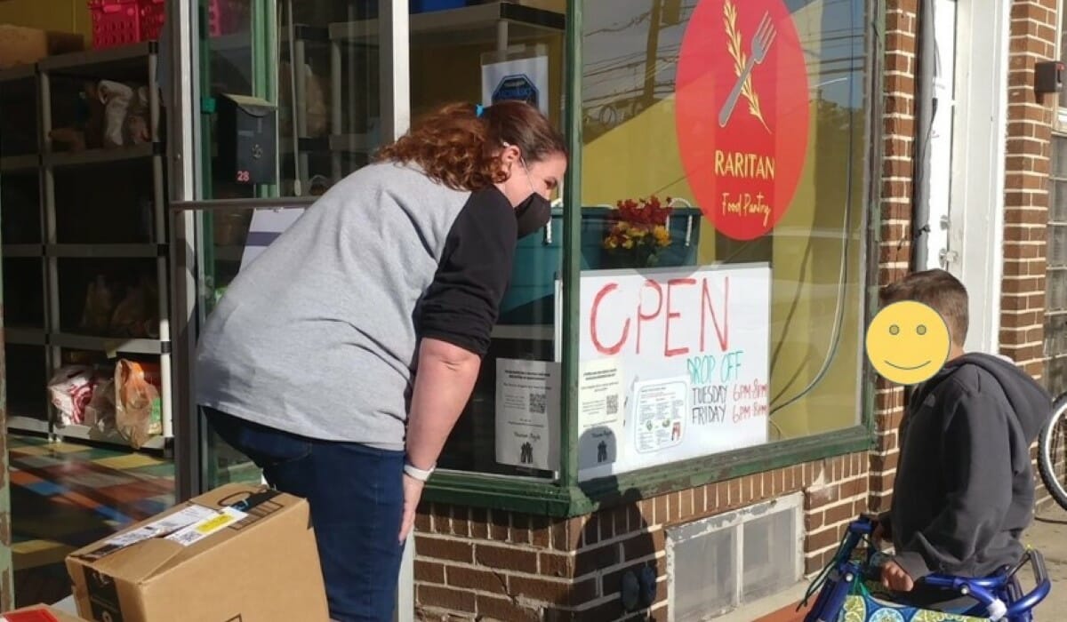 Woman and a small boy standing outside a food pantry with boxes of donations