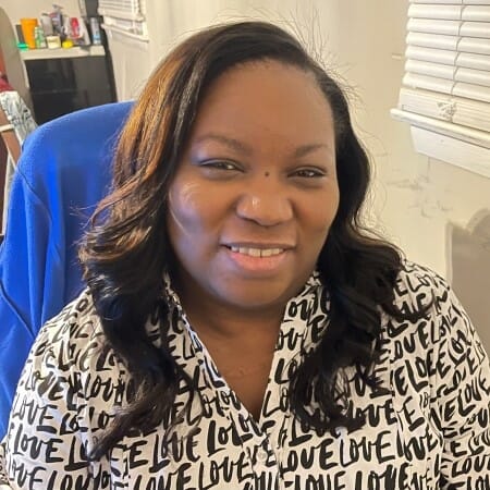 Headshot of a smiling woman wearing a white shirt emblazoned with the word "Love".