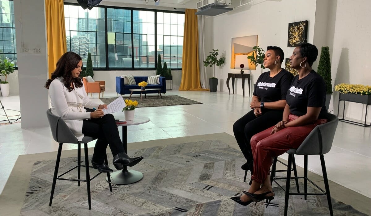 Two women seated in a TV studio being interviewed by a third woman.