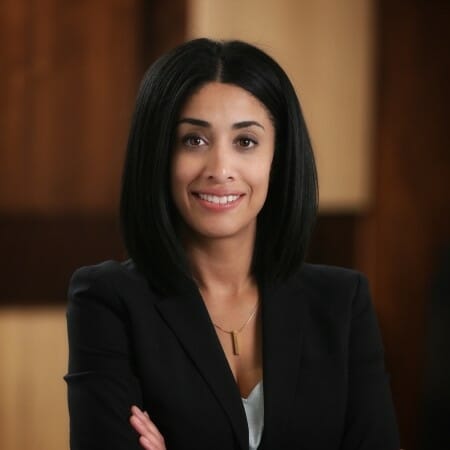 Headshot of a woman with long dark hair wearing a black blazer.