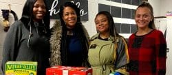 Four women pose with non-perishable food ready to be donated.