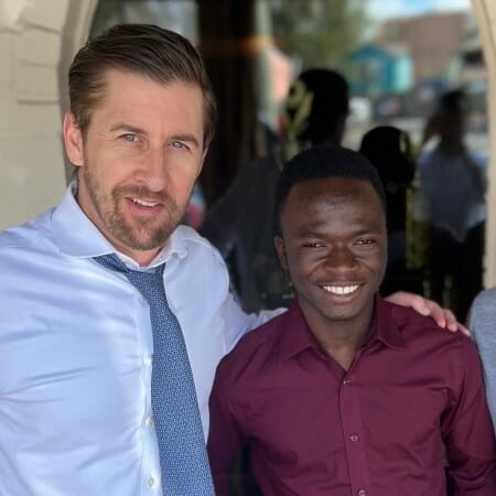 Two men in dress shirts pose together.