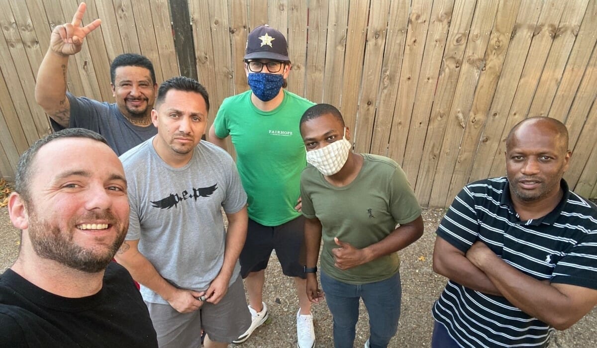 Group of men pose outdoors for a selfie.