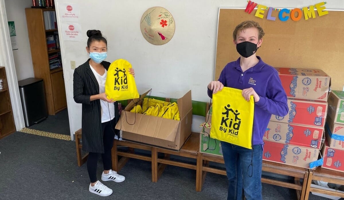 Two teenagers holding bags of donated school supplies.