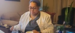 Woman in glasses sits working at a table.