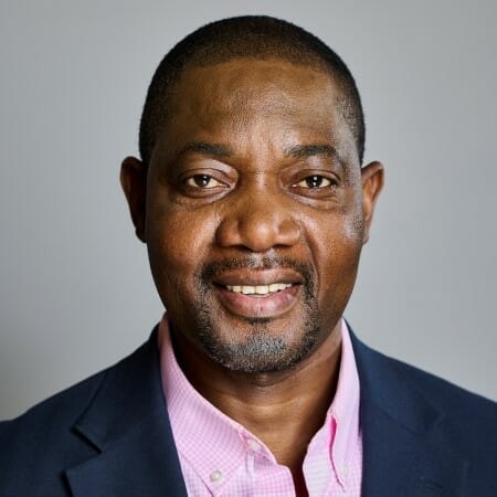 Headshot of a man in a blazer and pink shirt.