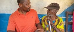 Two men, one holding a cane, sit together