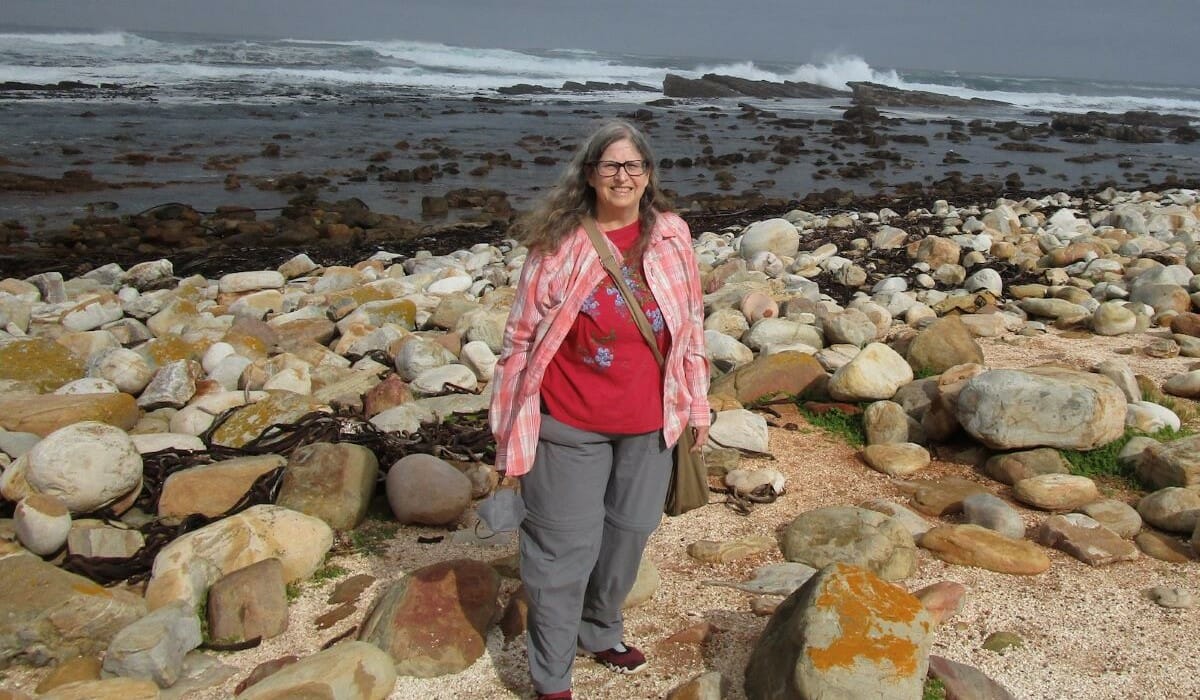 Woman standing on rocky beach in front of the ocean.