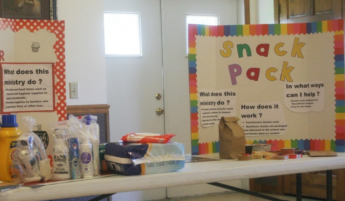 Folding tables with brown paper bags full of food and snacks.