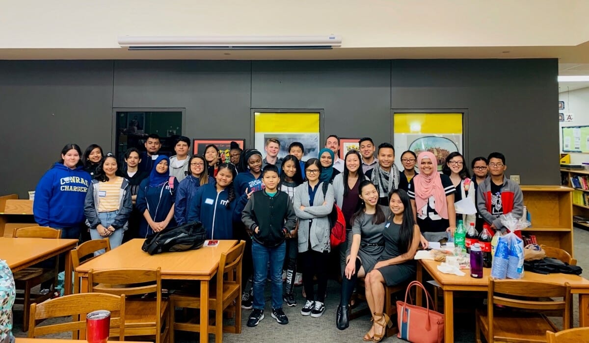 Large group of people posing in a classroom.