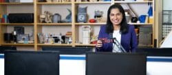 Woman in a blue blazer stands in a computer science lab.