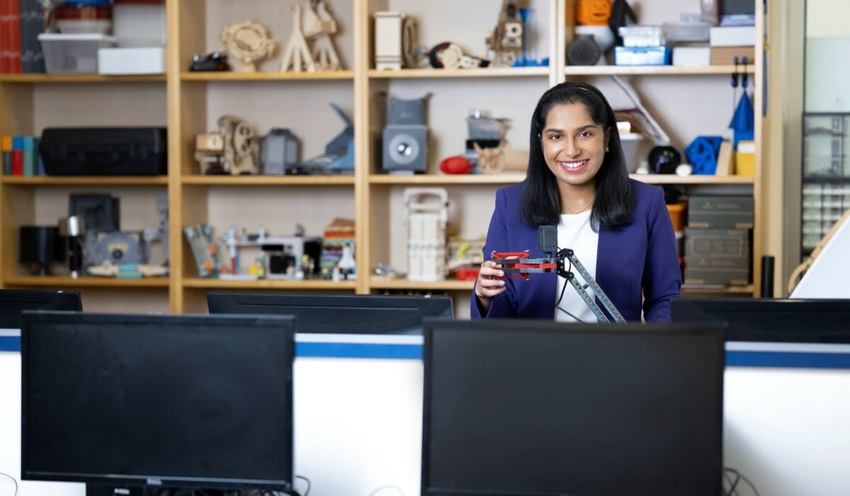 Woman in a blue blazer stands in a computer science lab.