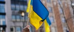Hand holding Ukrainian flag with cityscape in background