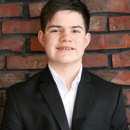 Headshot of a teenager in a black blazer and white shirt.